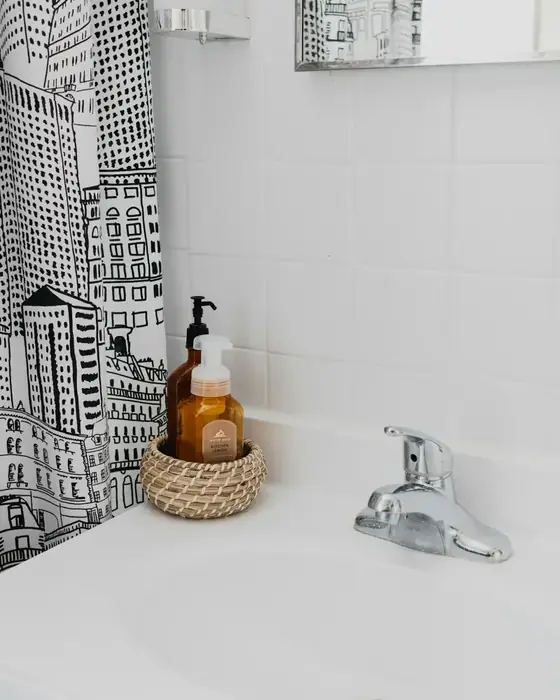 White basin with a chrome faucet and a woven basket of soap dispensers