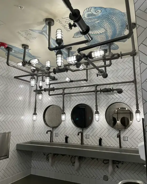 Industrial-style washroom with round mirrors and a long concrete basin